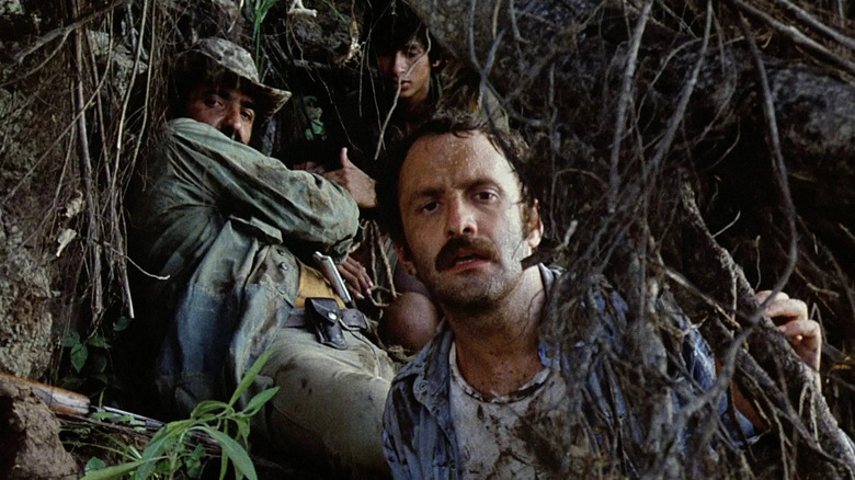 Professor Harold Monroe, Chaco and Miguel hiding among trees in Cannibal Holocaust