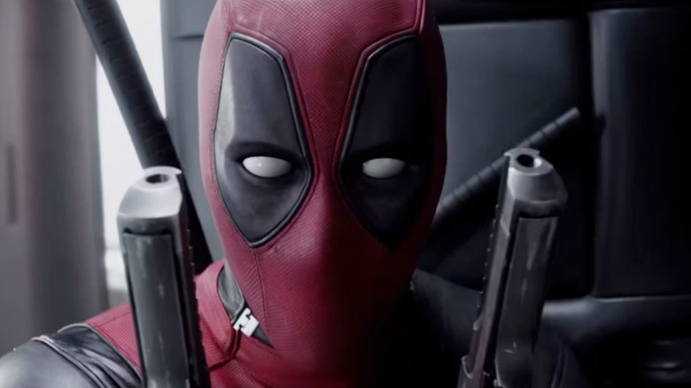 Deadpool dual-wielding guns in a car